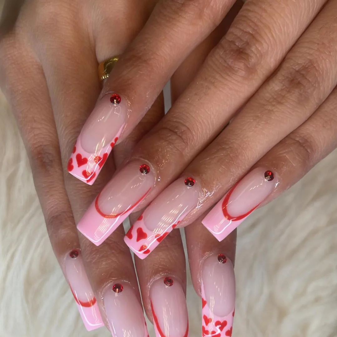 Pink square nails with red heart details and crystals by Your Way Nail Spa