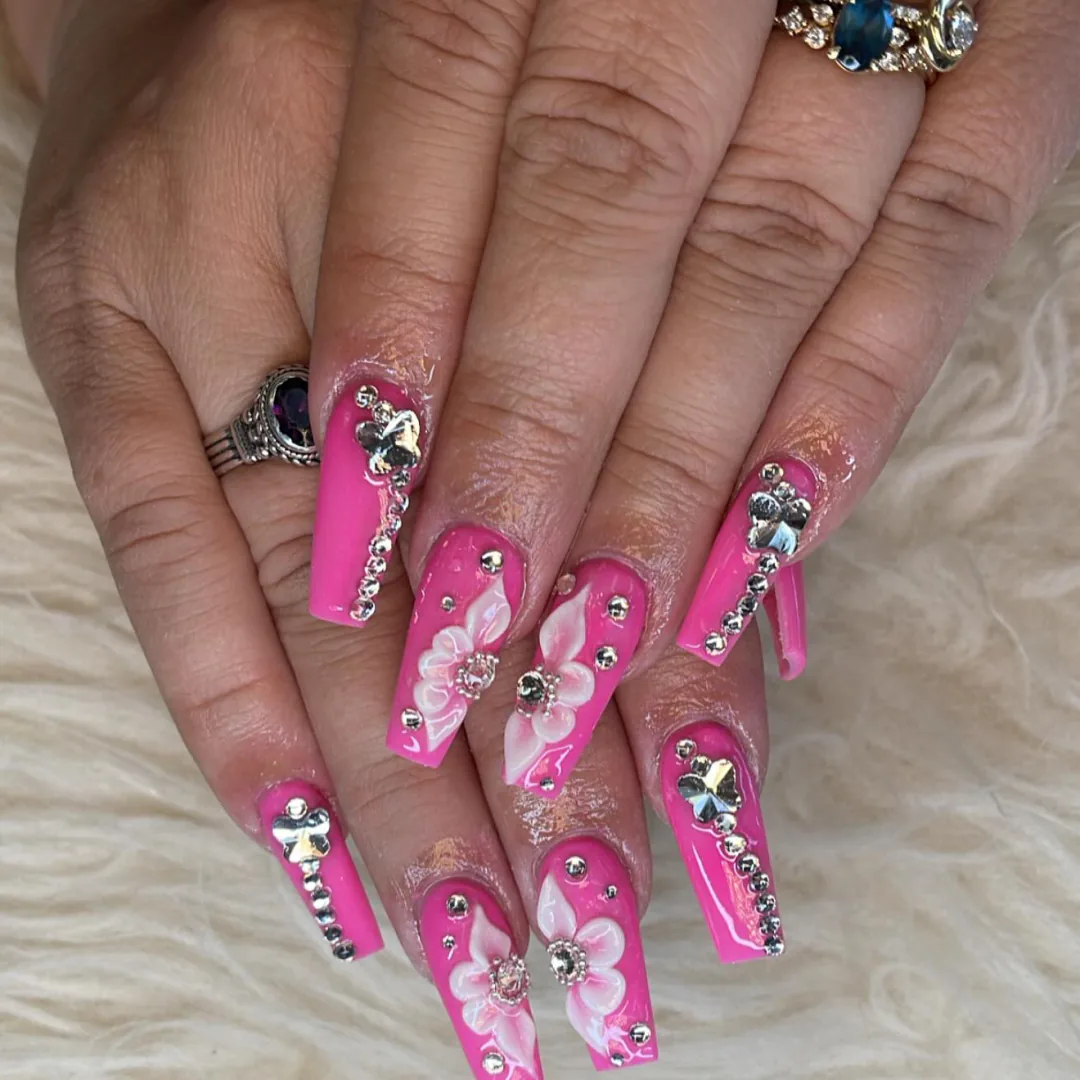 Bright pink coffin nails with white flowers and crystal accents by Your Way Nail Spa
